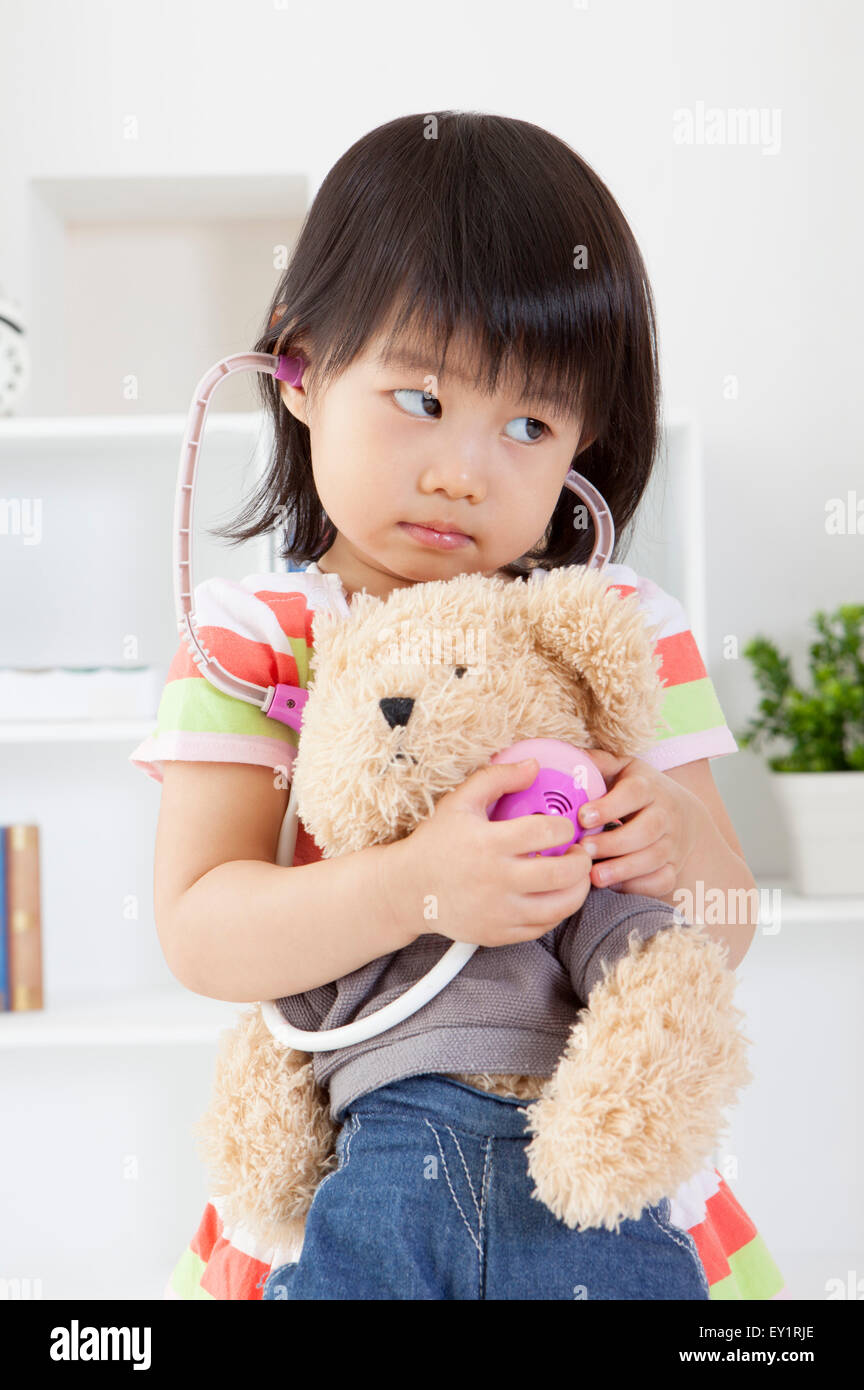 Little girl holding teddy bear and looking away Stock Photo - Alamy