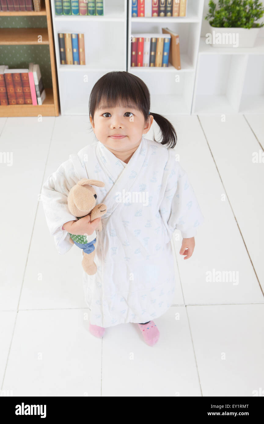 Little girl standing and holding teddy bear Stock Photo - Alamy