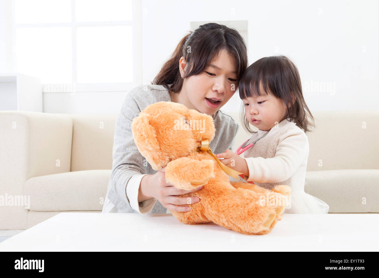 Mother and baby girl holding teddy bear together Stock Photo - Alamy