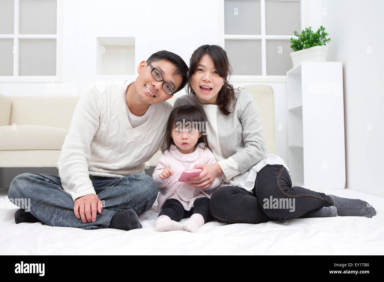 Family with one child sitting and smiling at the camera together, Stock Photo