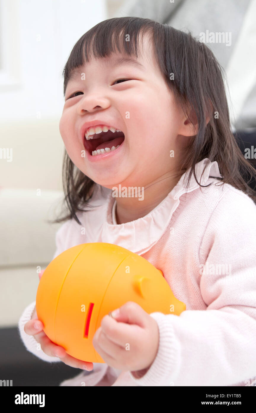 Baby girl holding piggy bank and smiling happily Stock Photo - Alamy