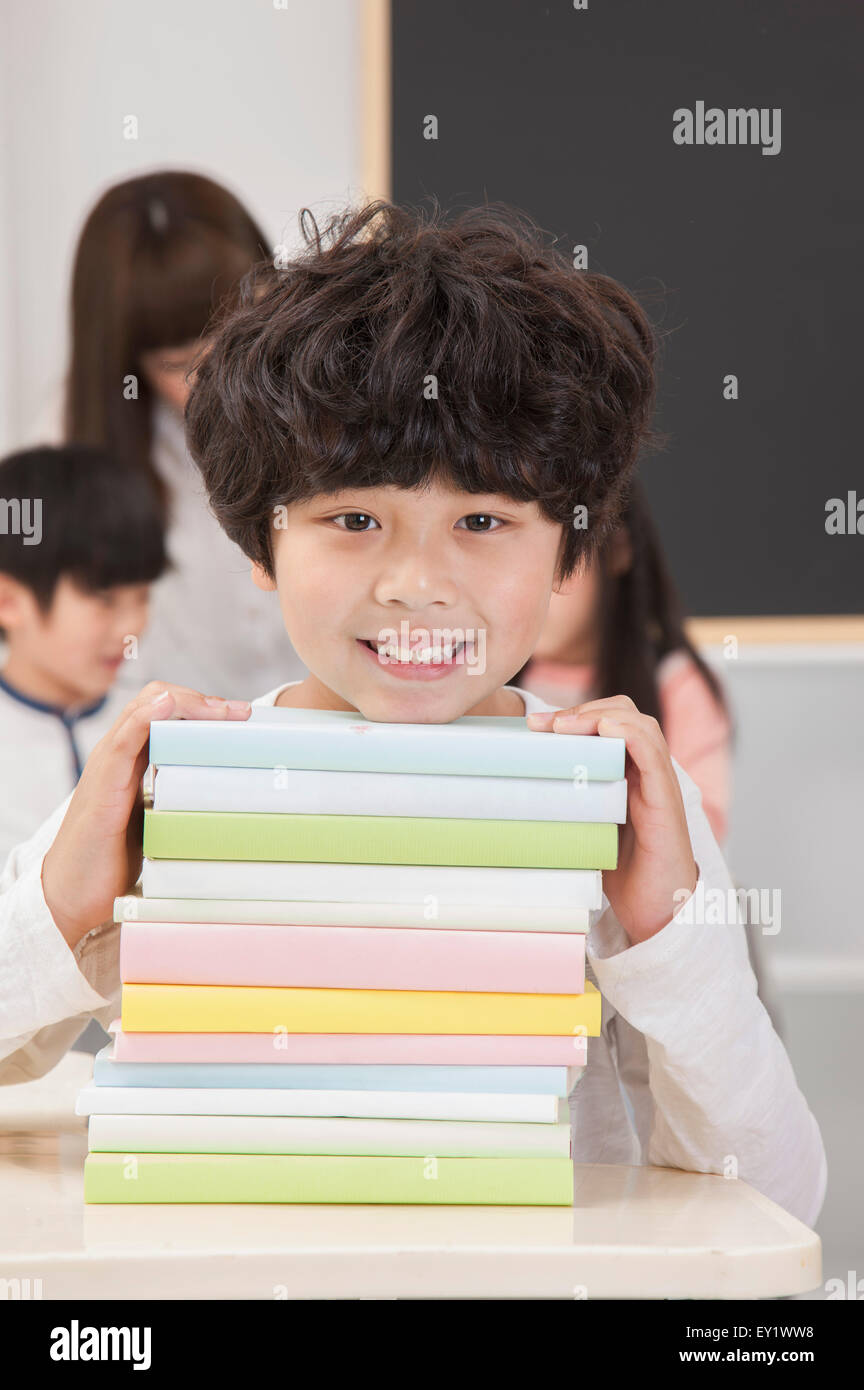 Boy holding a stack of books and smiling at the camera, Stock Photo