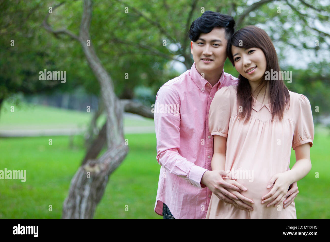 Young man embracing pregnant woman and smiling happily Stock Photo - Alamy