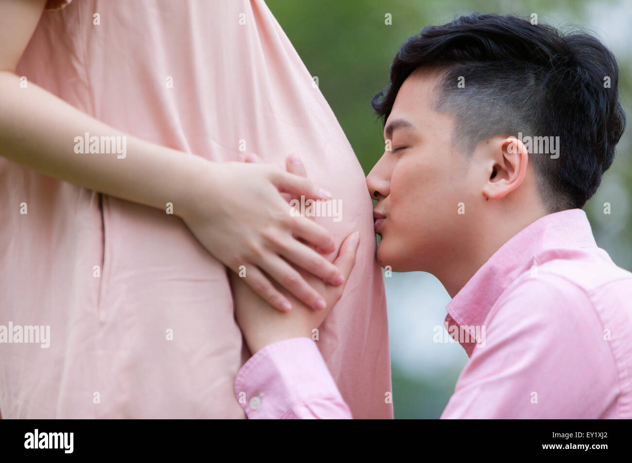 Young man kissing pregnant woman's abdomen, Stock Photo