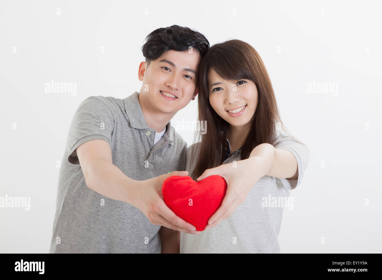 Young couple holding a red heart shape and smiling at the camera Stock ...