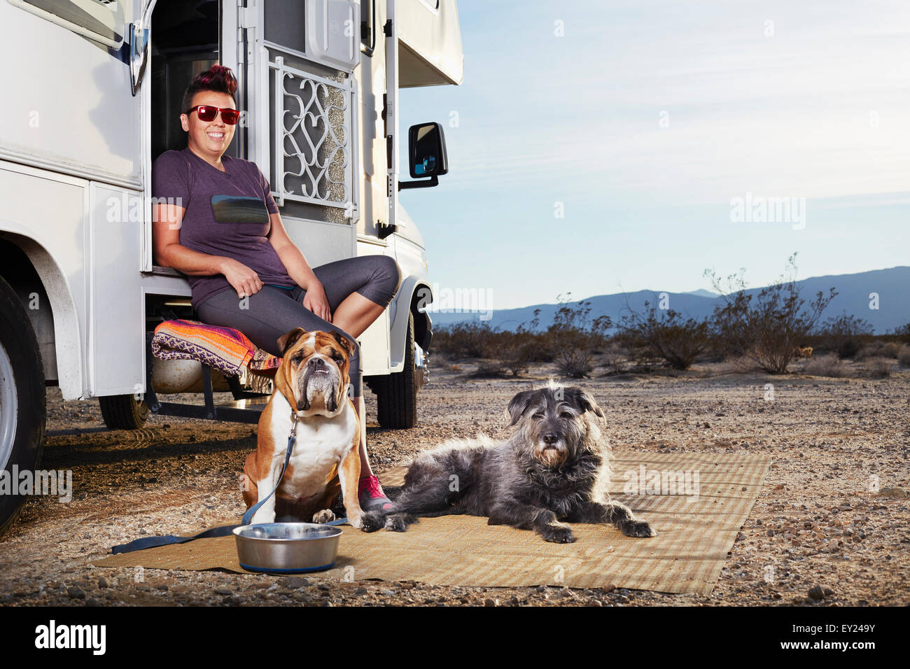 Portrait of mid adult woman and two dogs sitting on camper van step, Borrego Springs, California, USA Stock Photo
