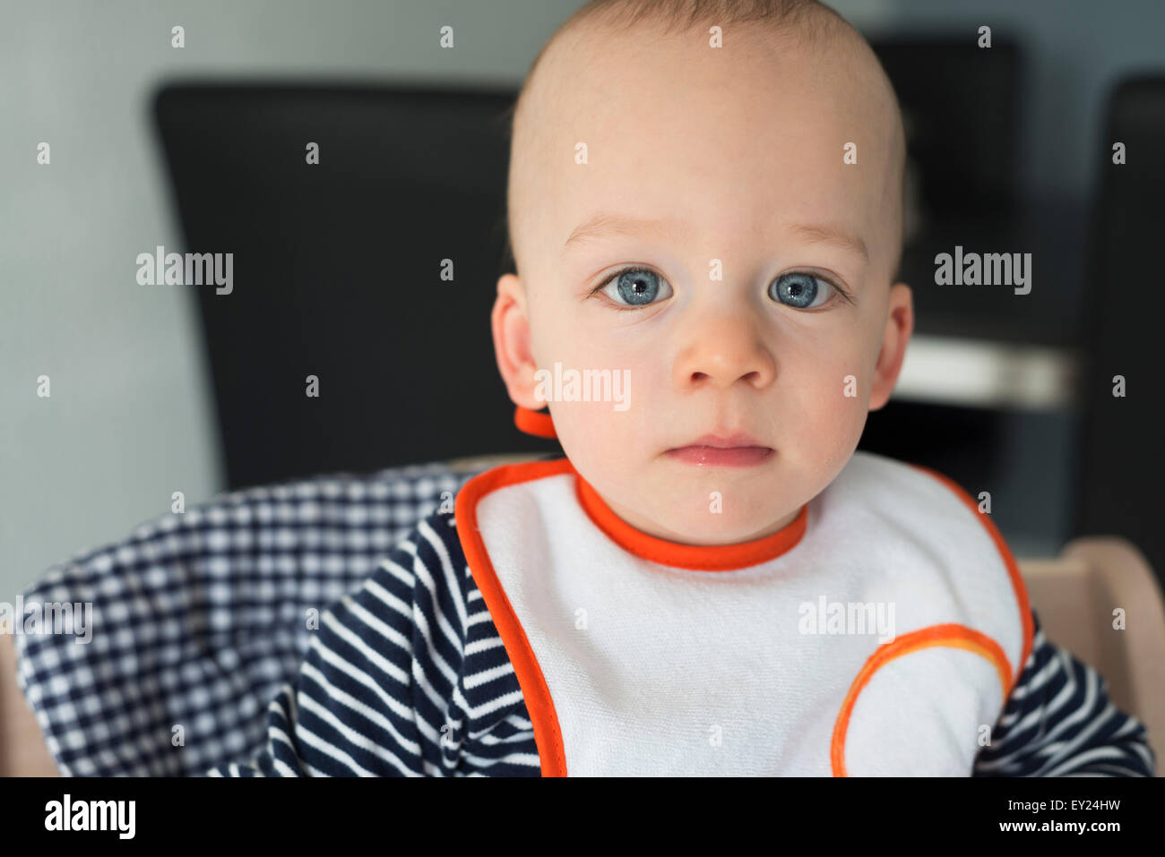 Portrait of staring baby boy in high chair Stock Photo