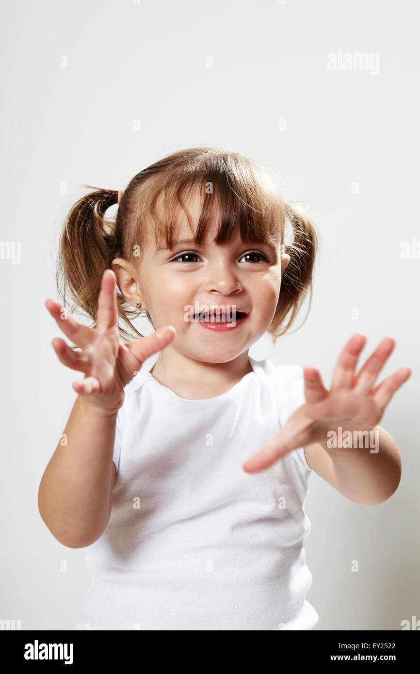 Portrait of young girl with pigtails, with hands up Stock Photo