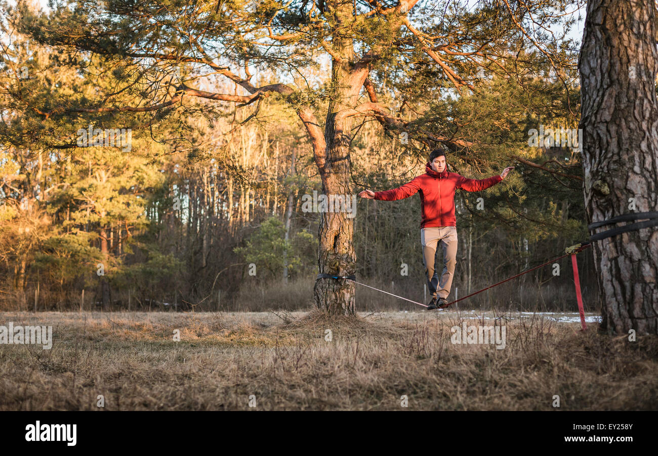 Young man balancing on slackline in forest Stock Photo