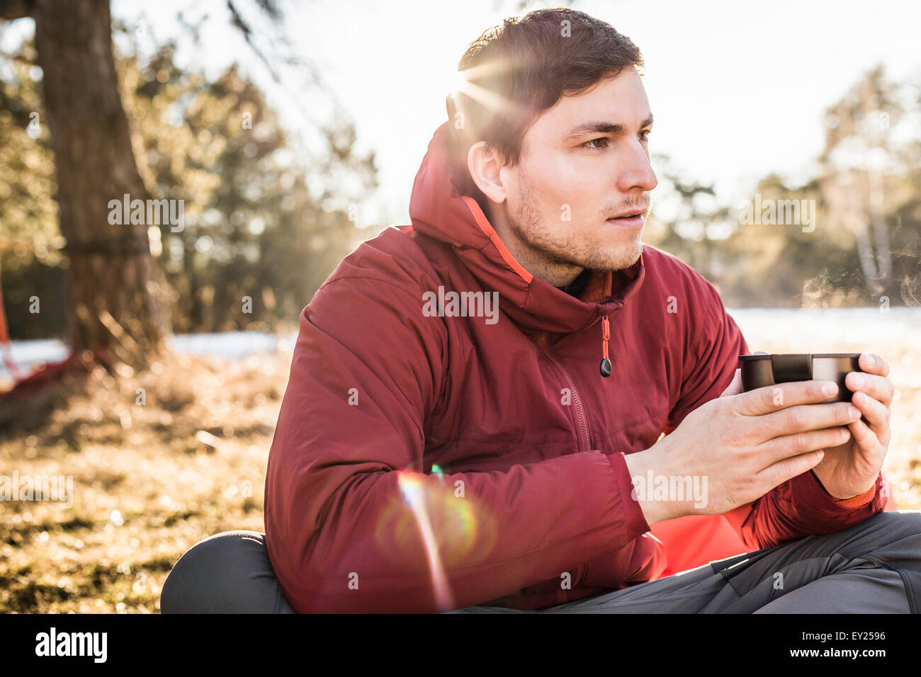 Young man sitting drinking coffee at lakeside Stock Photo