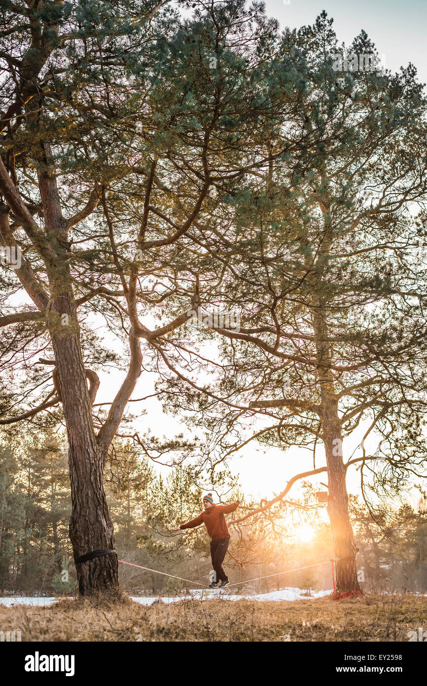 Young man balancing on slackline in lakeside forest Stock Photo