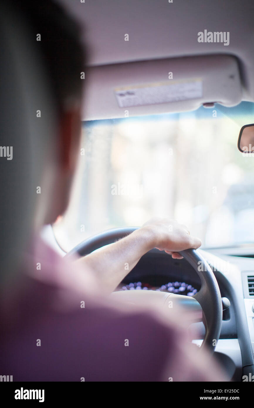 Over the shoulder view of young businessman driving car Stock Photo