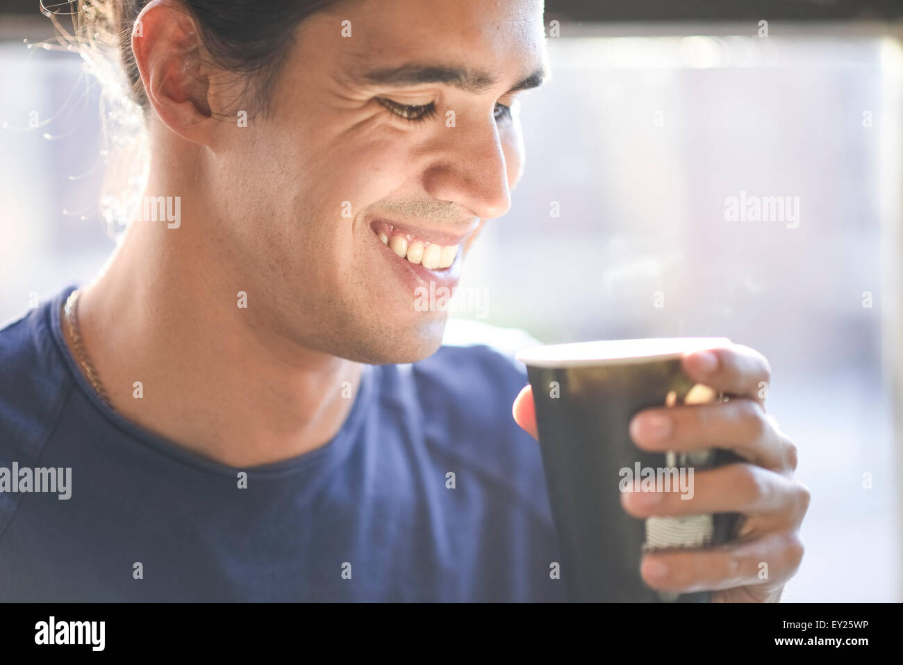 Young man holding coffee cup, indoors Stock Photo