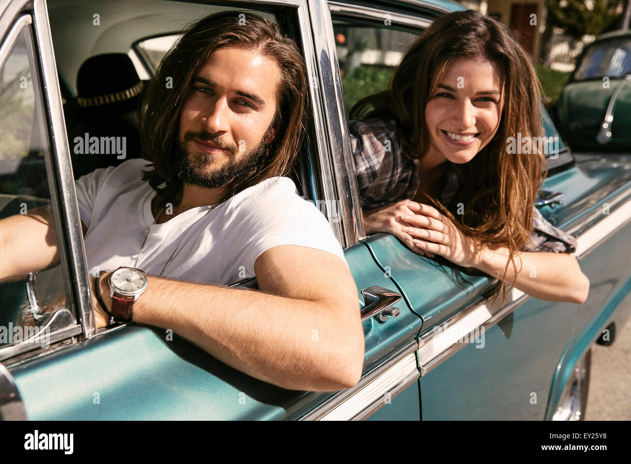 Young couple leaning out of vintage car windows Stock Photo