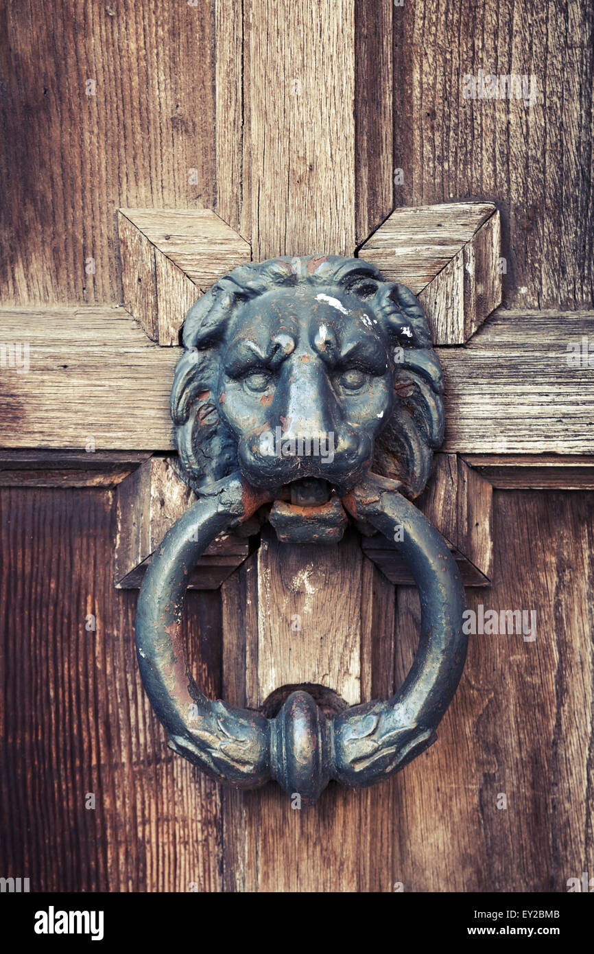 Old doorknob in shape of lion head on vintage wooden door, vintage tonal correction filter Stock Photo