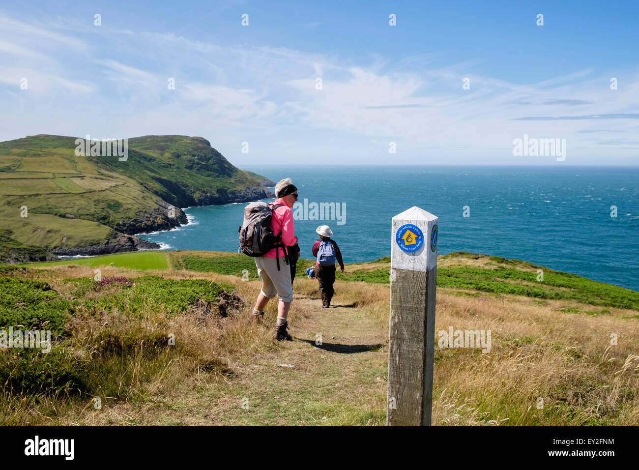 Hikers hiking on Wales Coast Path by coastal footpath sign on Lleyn Peninsula / Pen Llyn, Gwynedd, North Wales, UK, Britain Stock Photo