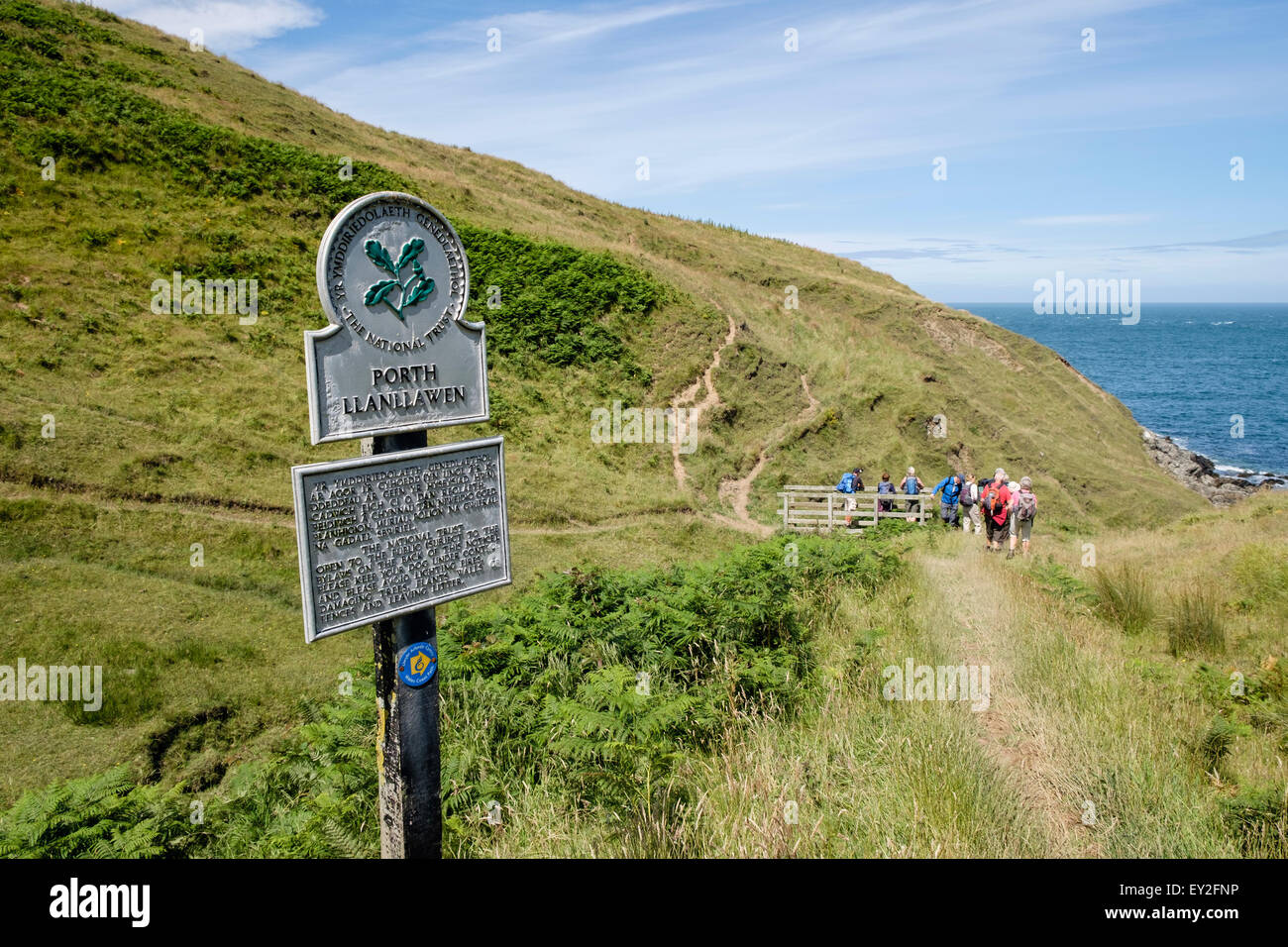 Sign on Wales Coast Path with hikers hiking at Porth Llanllawen Lleyn Peninsula / Pen Llyn Gwynedd North Wales UK Stock Photo