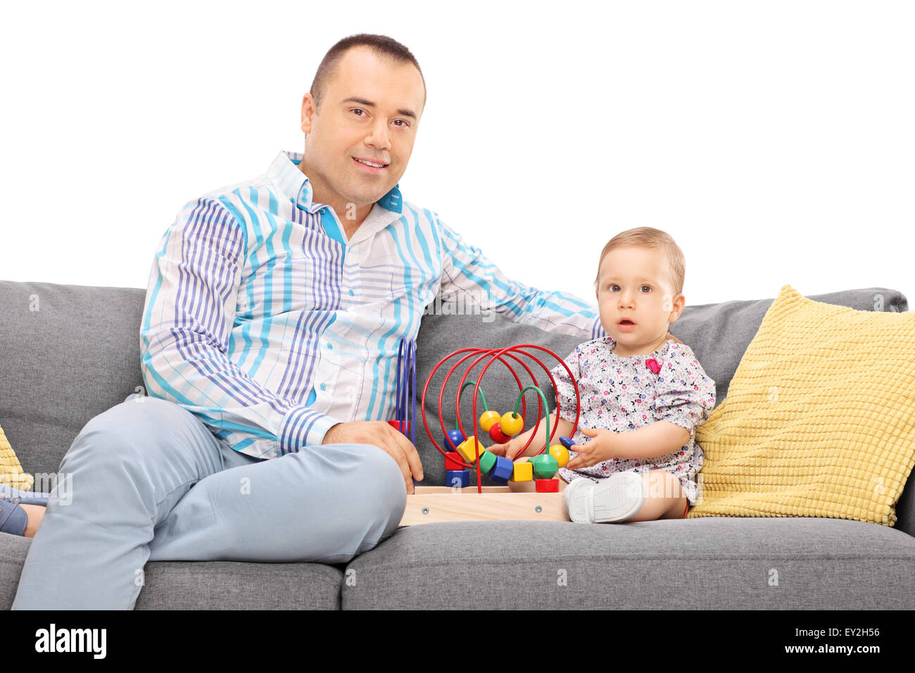 Young father posing seated on a gray sofa with his baby daughter isolated on white background Stock Photo