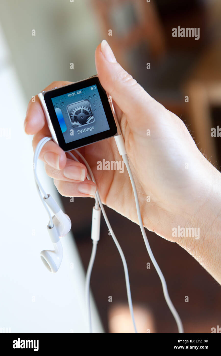 Close up of an Apple iPod nano, with headphones, held in a womans hand showing the settings screen. Stock Photo