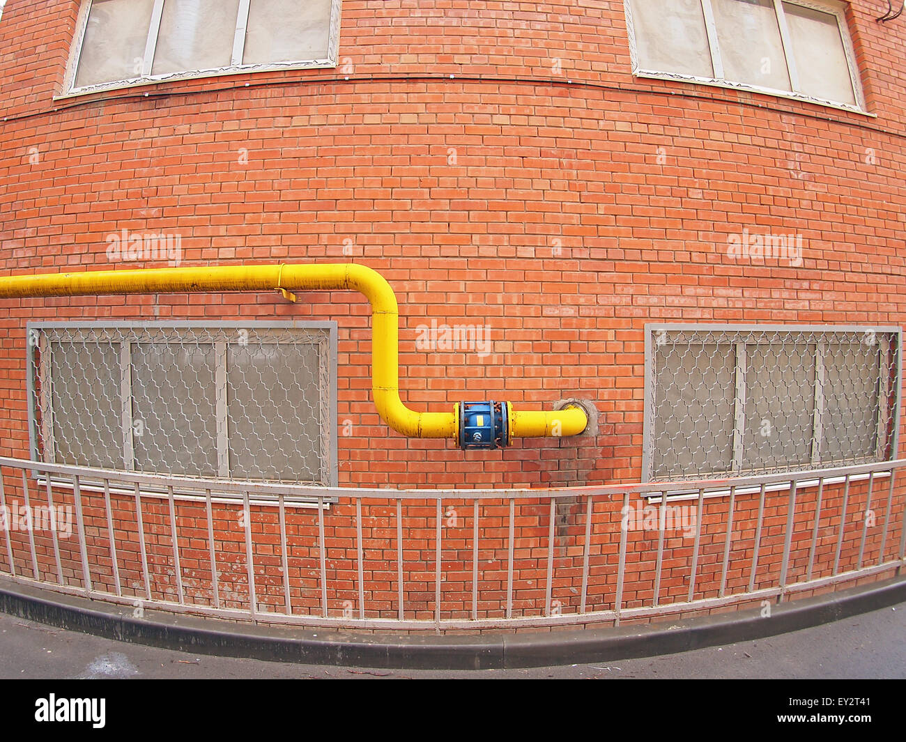 Wall of a building with a yellow gas pipe and windows with wide angle fisheye Stock Photo