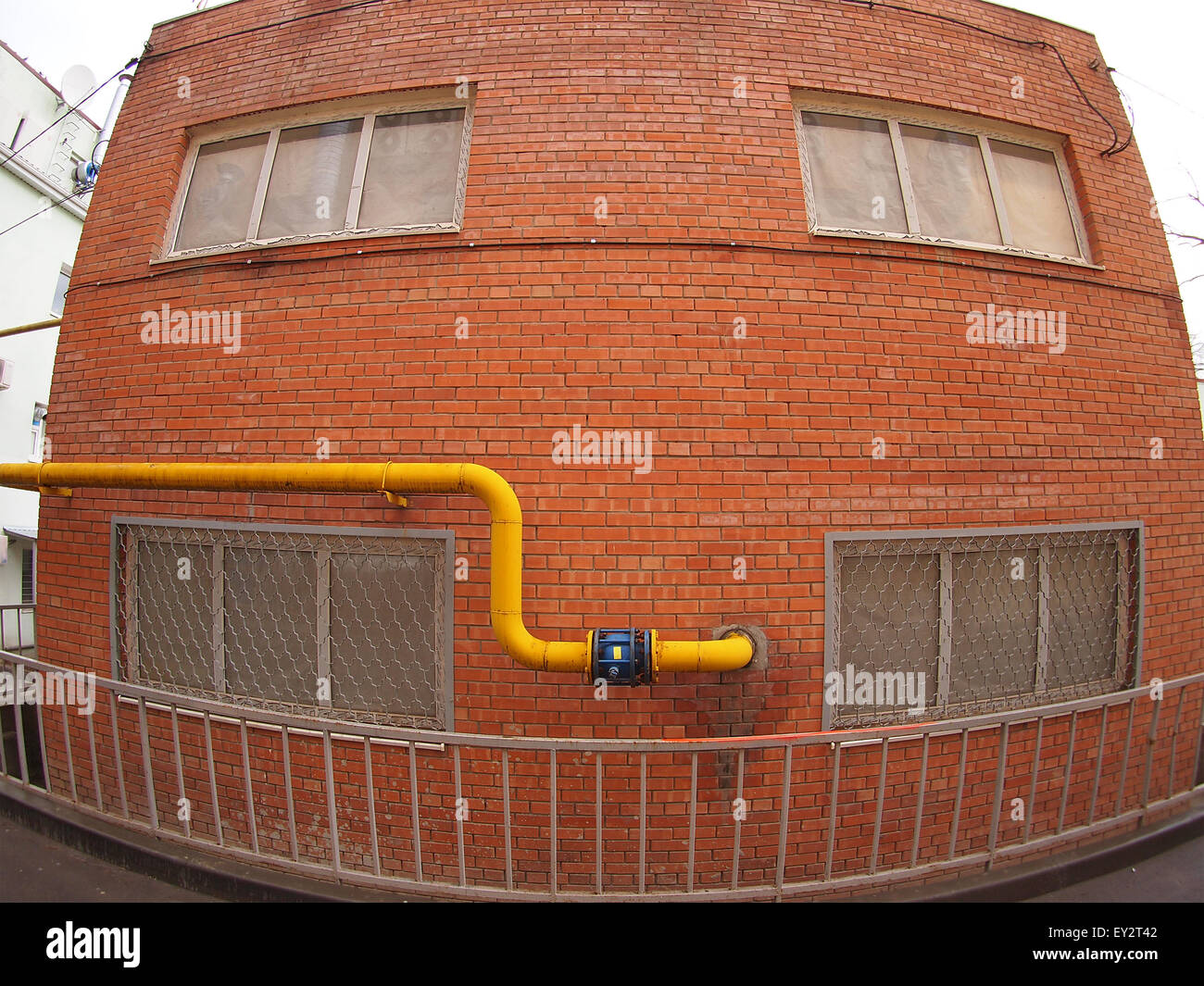 Wall of a building with a yellow gas pipe and windows with wide angle fisheye view Stock Photo