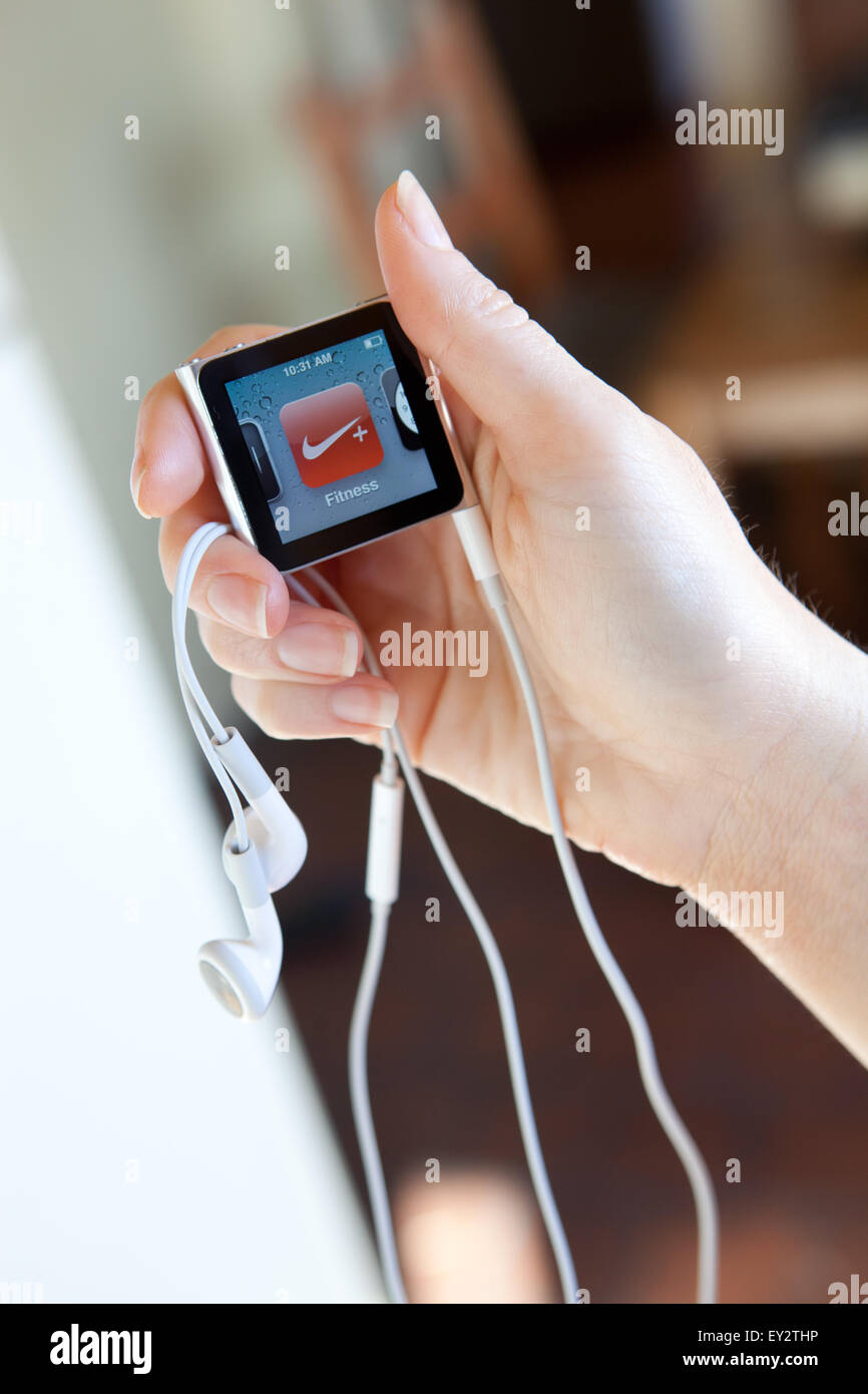 Close up of an Apple iPod nano, with headphones, held in a womans hand showing the fitness screen. Stock Photo