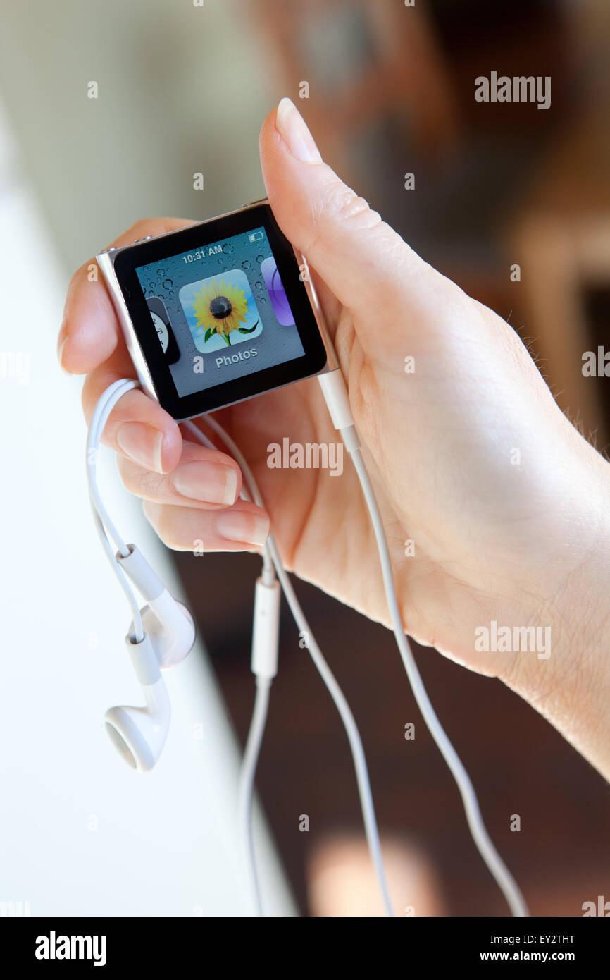 Close up of an Apple iPod nano, with headphones, held in a womans hand showing the photos screen. Stock Photo