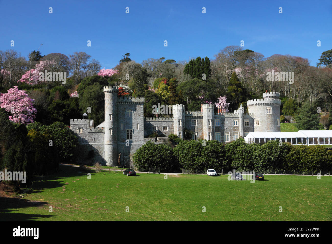 A turreted castle in parkland set against a backdrop of magnolias and camelias. Stock Photo