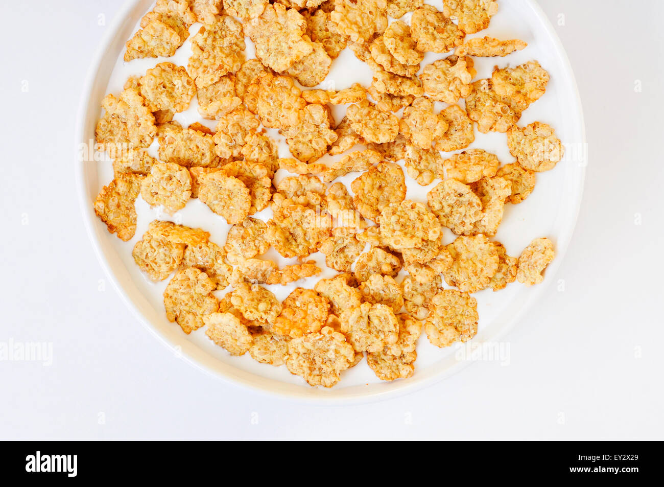 high-angle shot of a white bowl with breakfast cereals soaked in milk on a white table Stock Photo