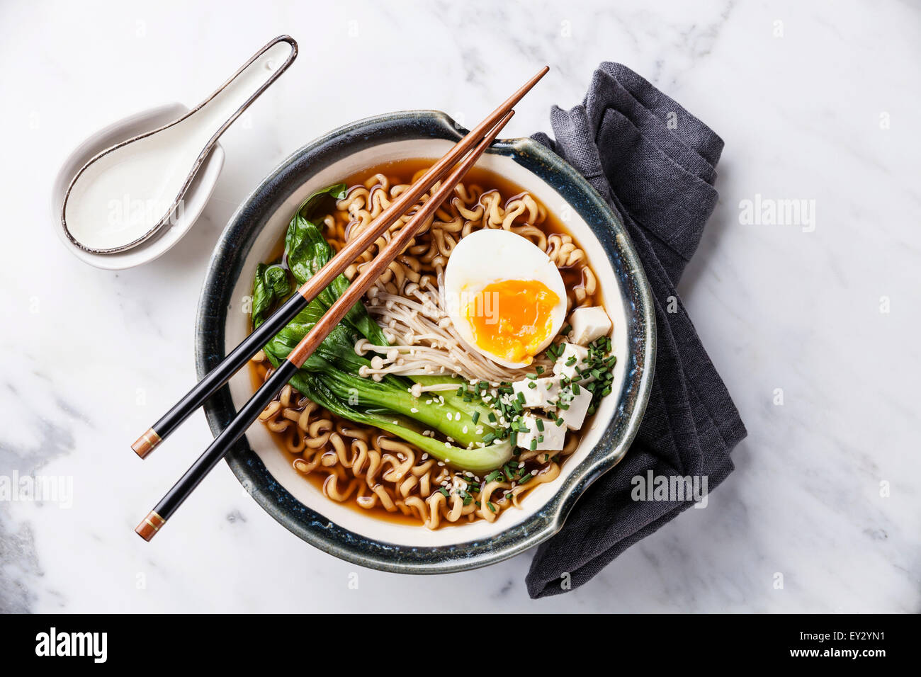Miso Ramen Asian noodles with egg, enoki and pak choi cabbage in bowl on white marble background