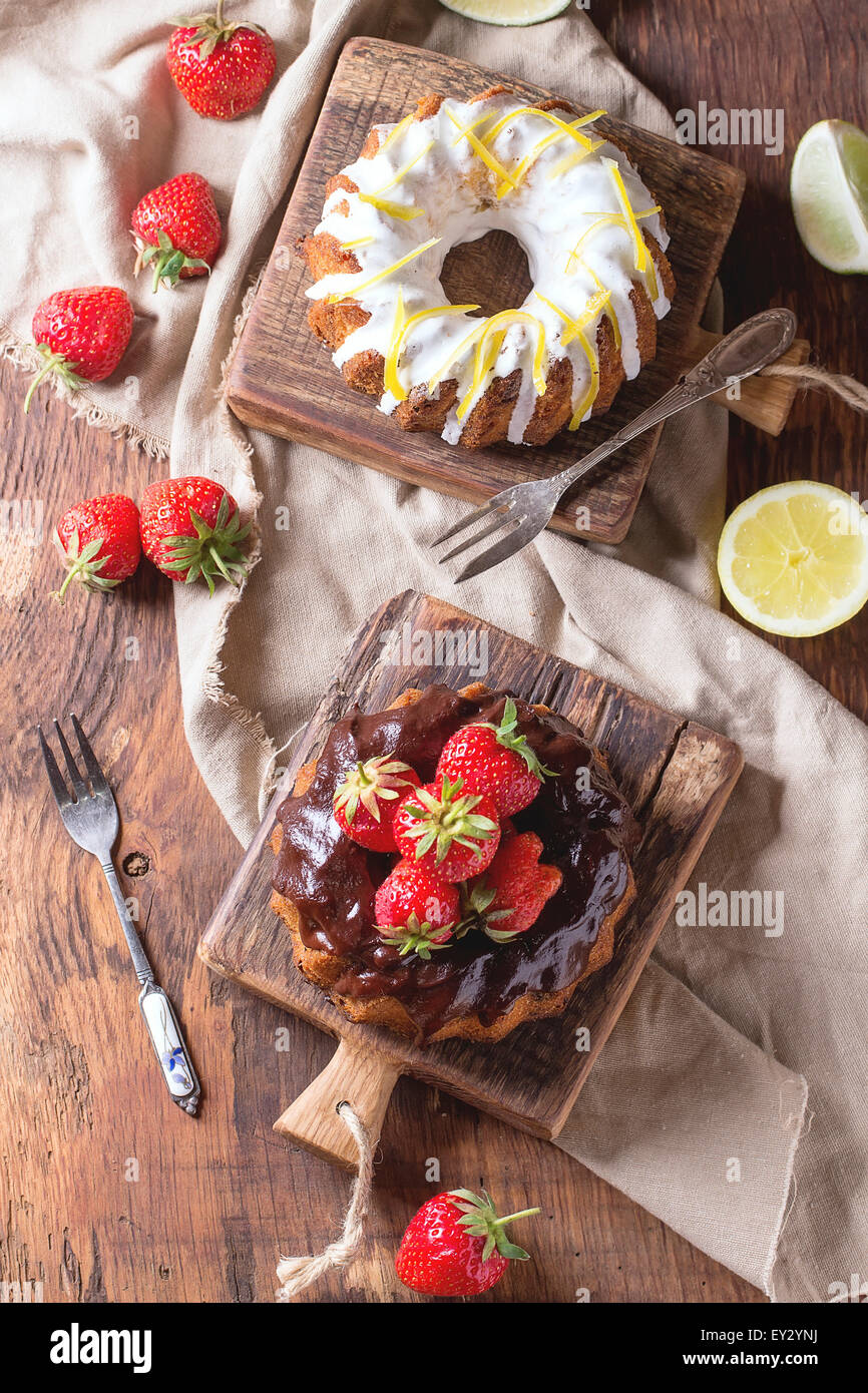 Homemade chocolate cakes with strawberries and dark chocolate ganache, and white frosting and lemon zest, served on small wooden Stock Photo
