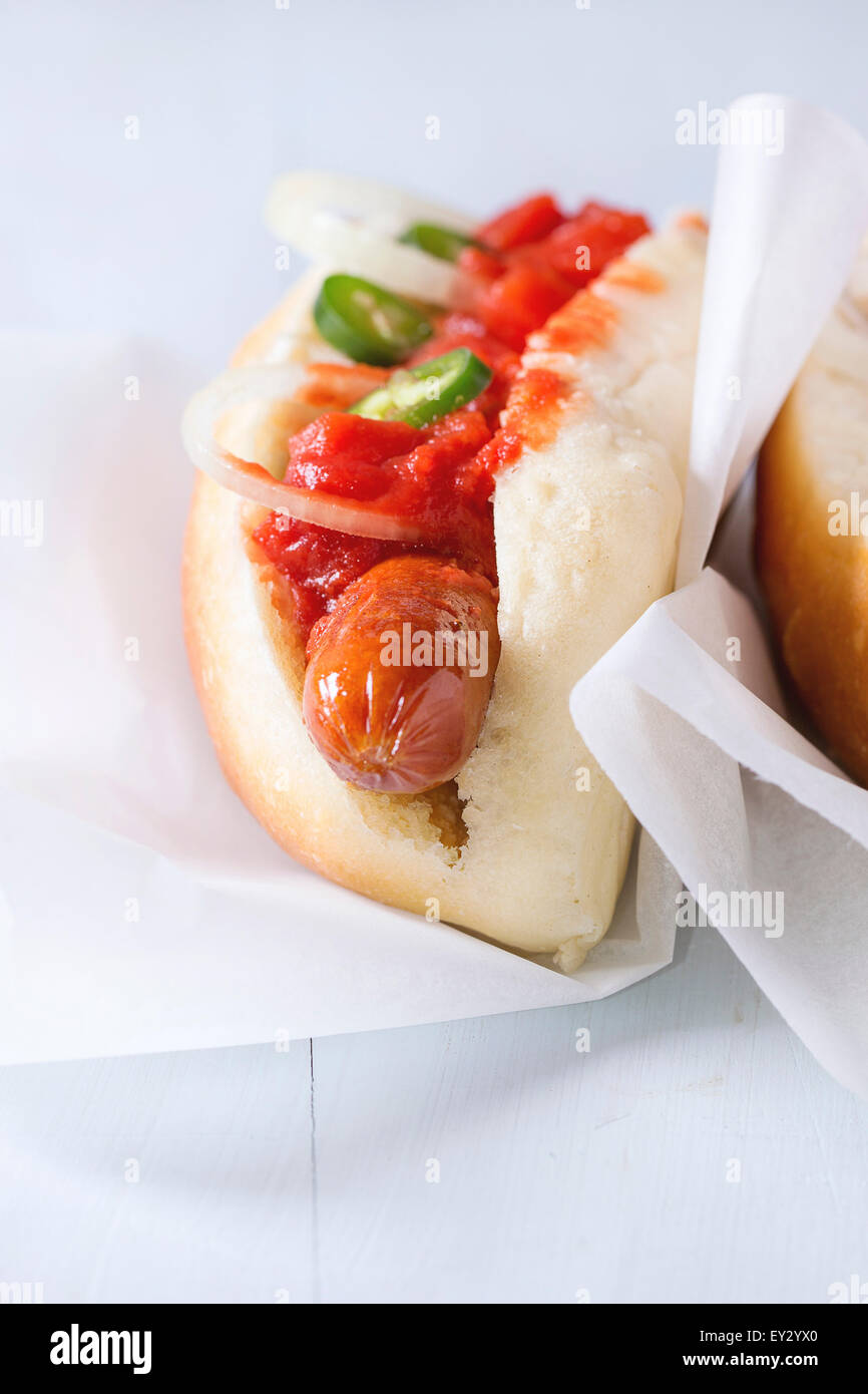 Homemade hot dogs on baking papper with tomato sauce, onion, pepper on
