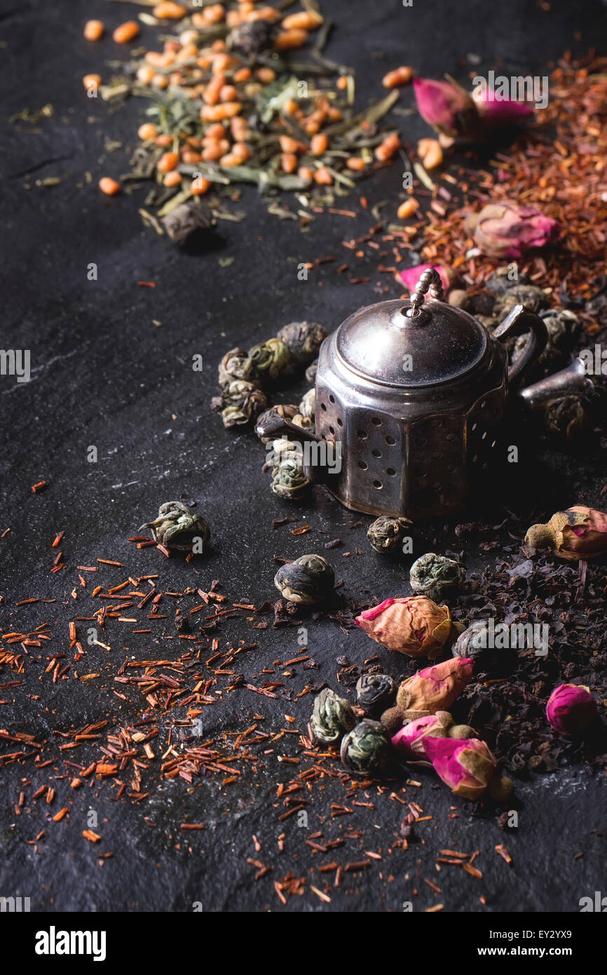 Assortment of dry tea with tea strainer as small teapot. Green tea, black tae, green tea with rice, rooibos, dry rose buds. Blac Stock Photo