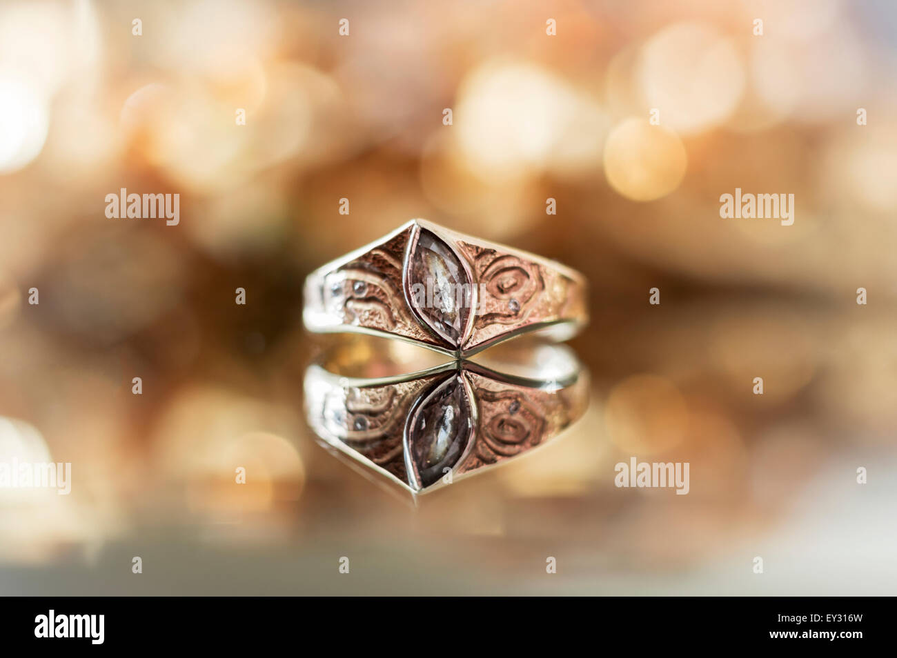 A diamond ring with a reflection, against a golden yellow light blurred