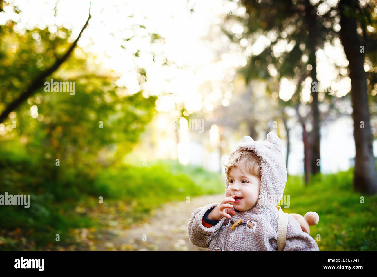 Funny Shy Little 2 year old Boy Giggling in the Park at the Sunset. Happy Childhood Concept. Space for your Text. Stock Photo