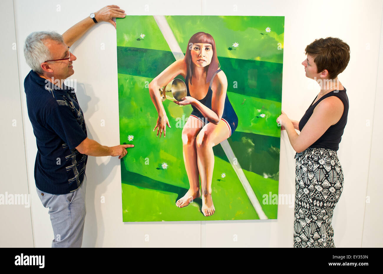 Mainz, Germany. 20th July, 2015. Oliver Schollenberger (L) and Selina Rosa Ruffing (R), organisers of the art exhibition 'Freistil' (lit. free style) mount an artwork entitled 'Having Won' by Ellen Akimoto to a wall in the lobby of the Landesbausparkasse Rheinland-Pfalz (lit. Rhineland-Palatinate state building association) in Mainz, Germany, 20 July 2015. Photo: Foto: Christoph Schmidt/dpa/Alamy Live News Stock Photo