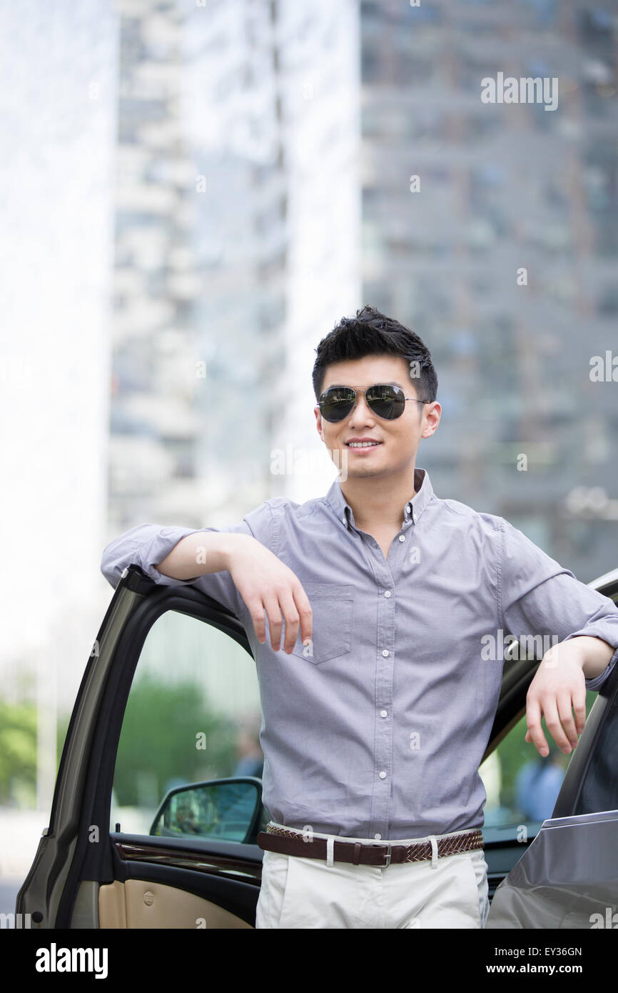 Young man standing next to his car Stock Photo - Alamy