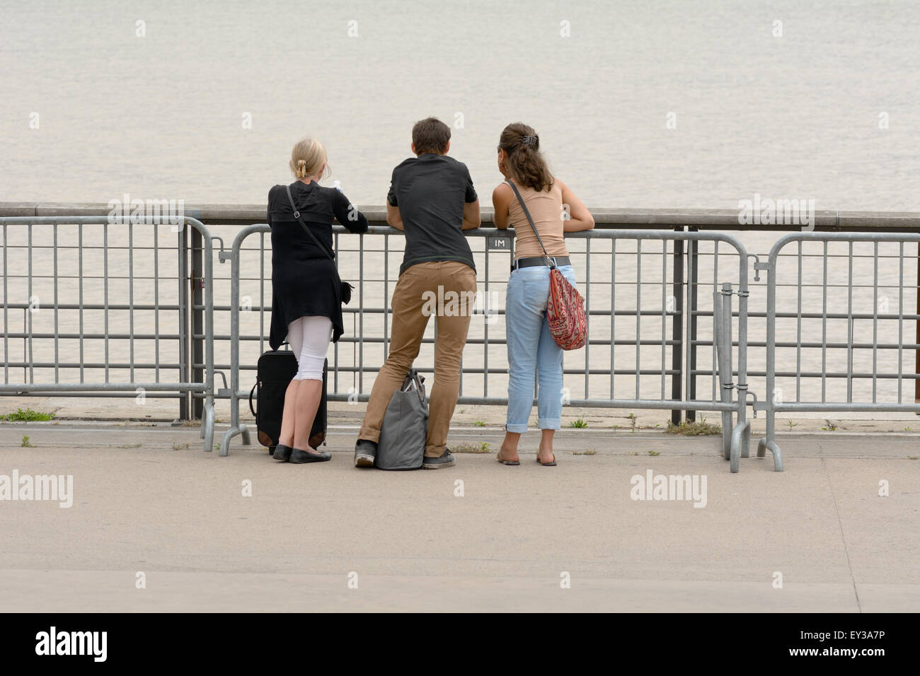 Three people leaning on railings looking across Garrone River in ...