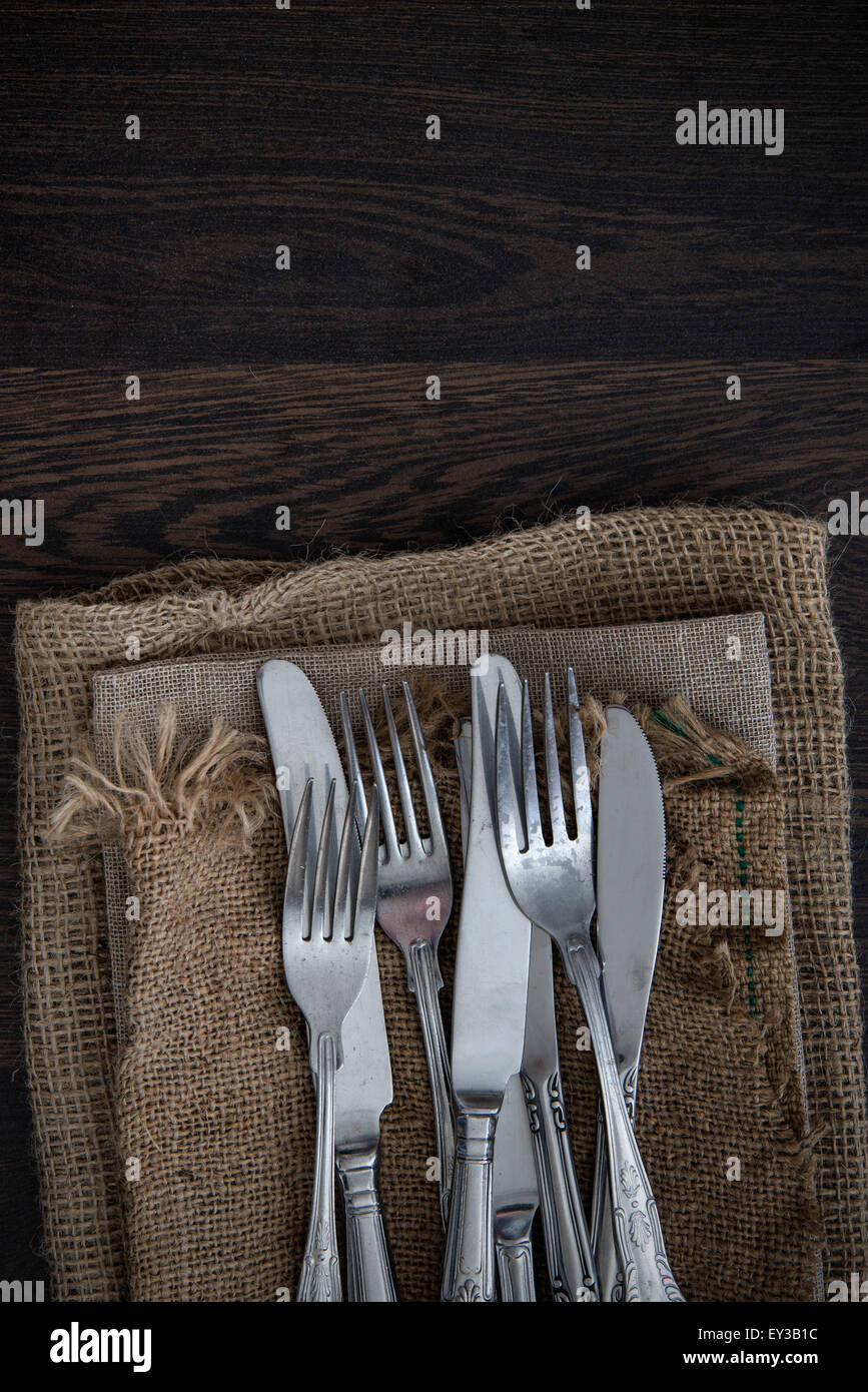 Vintage cutlery on hessian cloths on wooden background Stock Photo