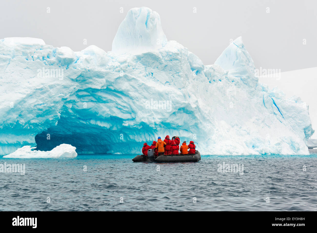 Group of people crossing the ocean in the Antarctic in a rubber boat, icebergs in the background. Stock Photo