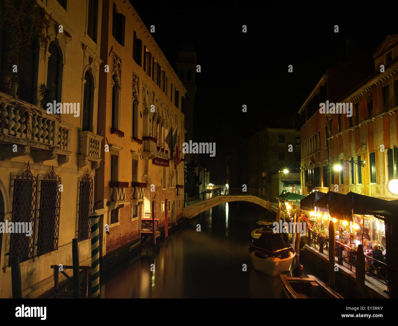 View of a canal in the city of Venice with a canalside restaurant at night. Venice. Italy. Stock Photo