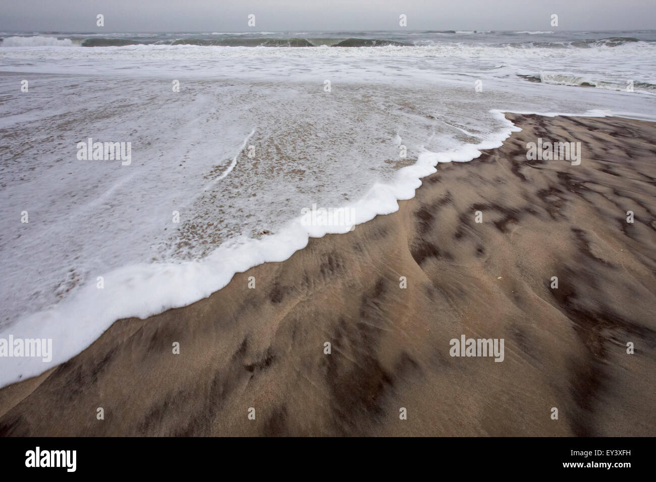 Waves lapping on the shore on a sandy beach. Stock Photo