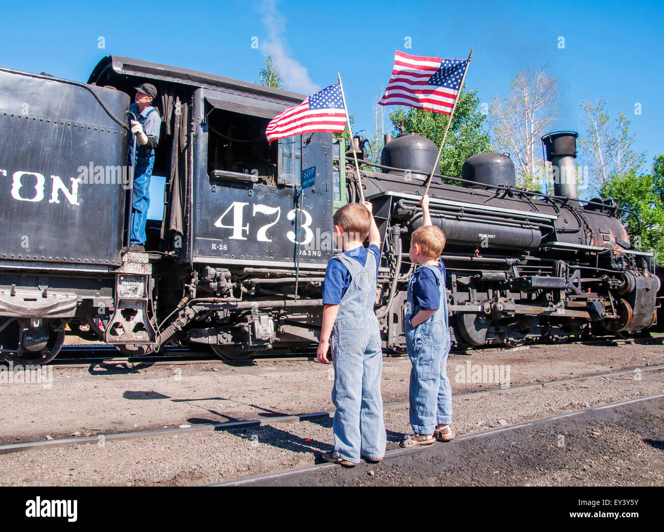 Train Conductor Engineer boys waving American flags Stock Photo