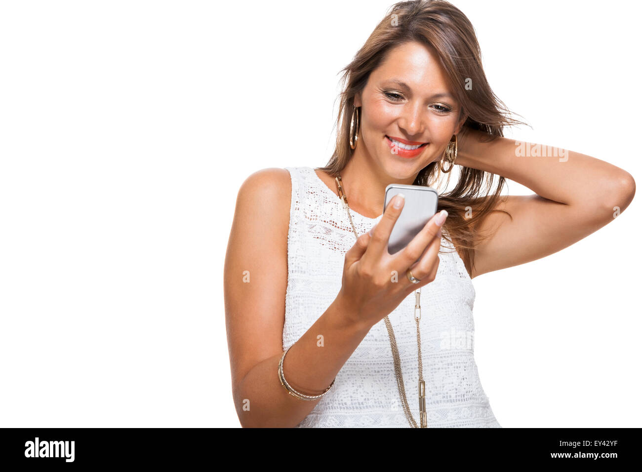 Vivacious attractive woman reacting to a text message on her mobile phone flicking her hair in the air and staring at the phone Stock Photo