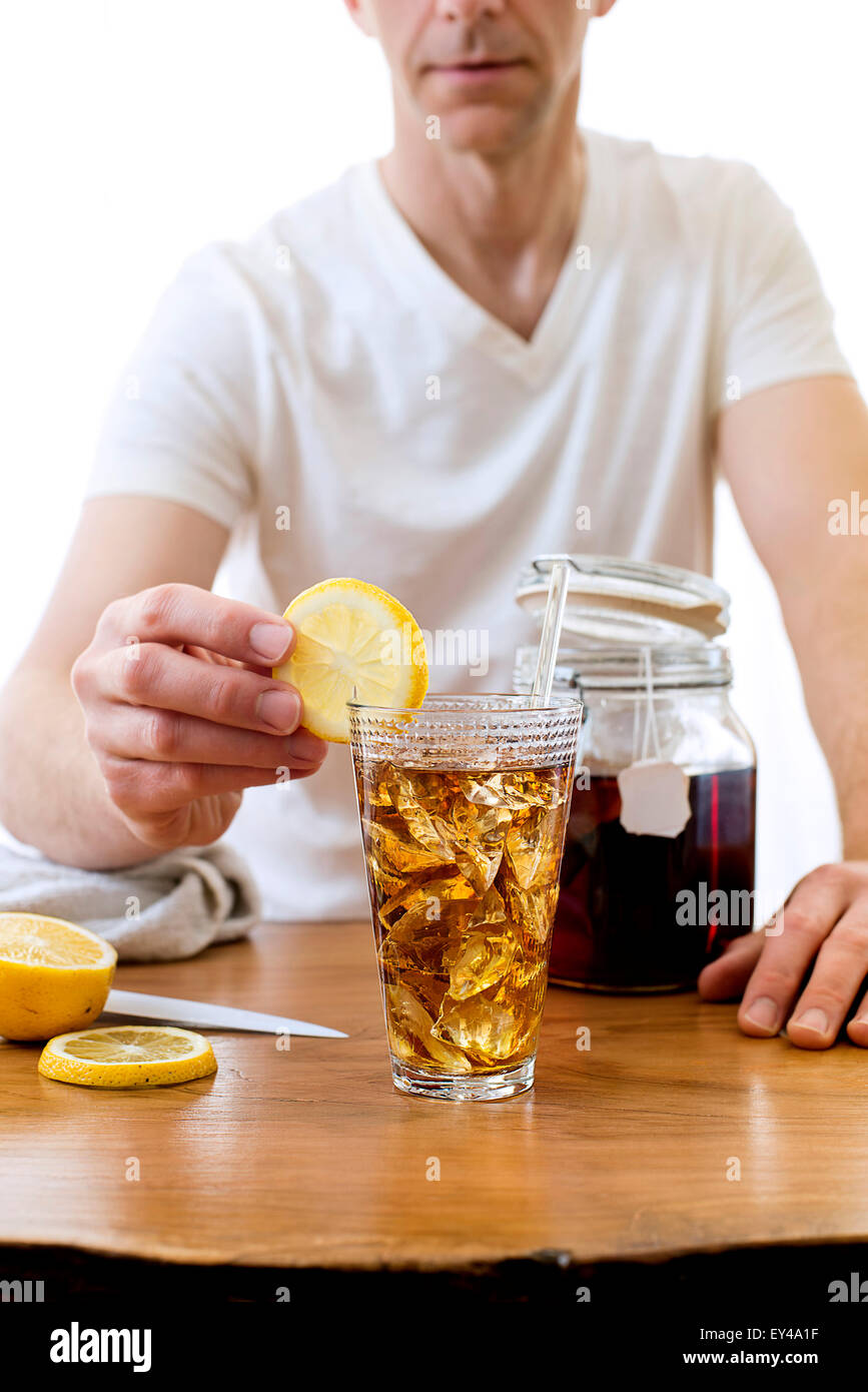 Man Putting Lemon Slice on Tall Glass of Iced Tea Stock Photo - Alamy