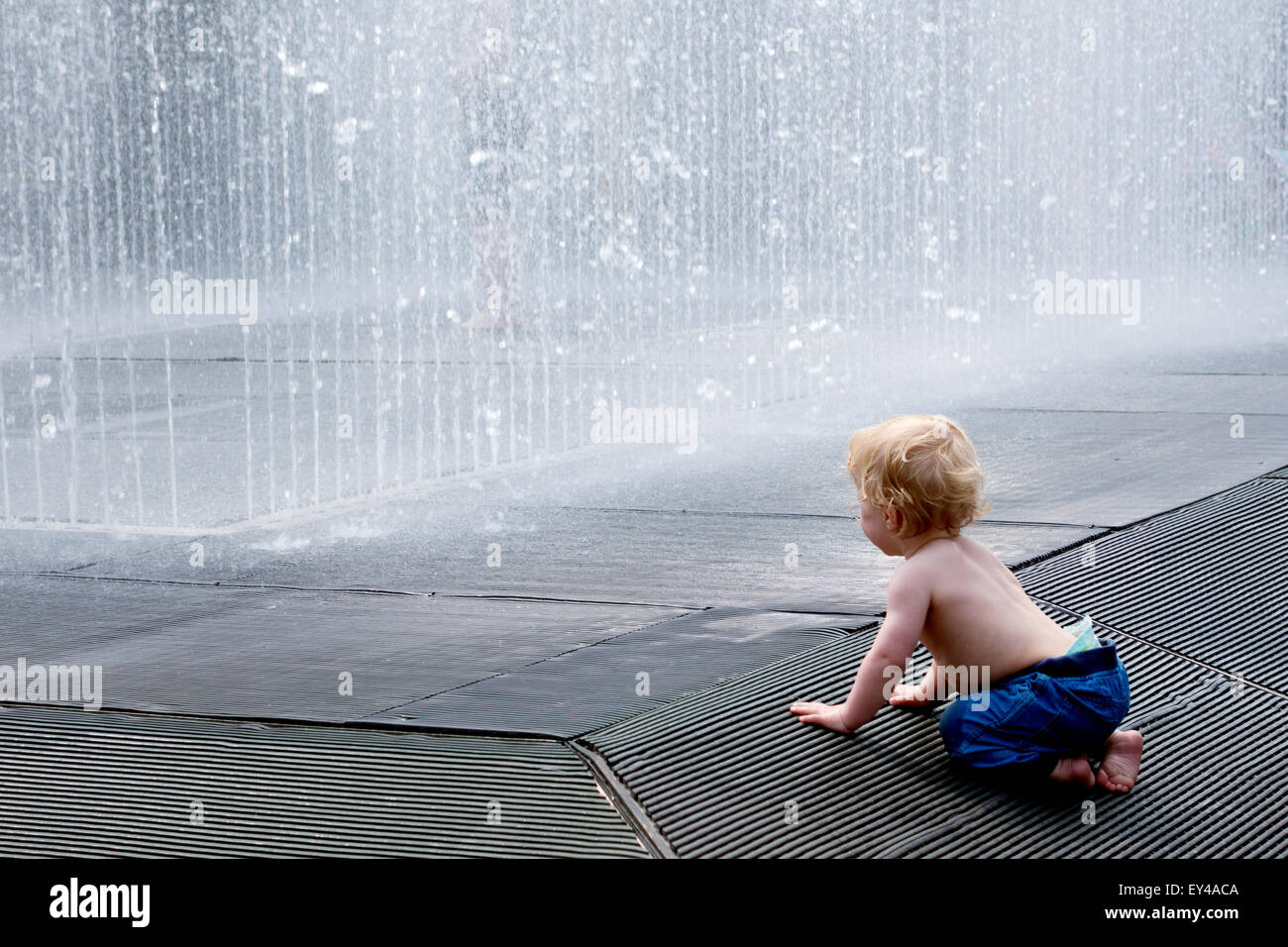 baby looking at a fountain on a hot afternoon, Concept - childhood discovery awe South Bank, London UK Stock Photo