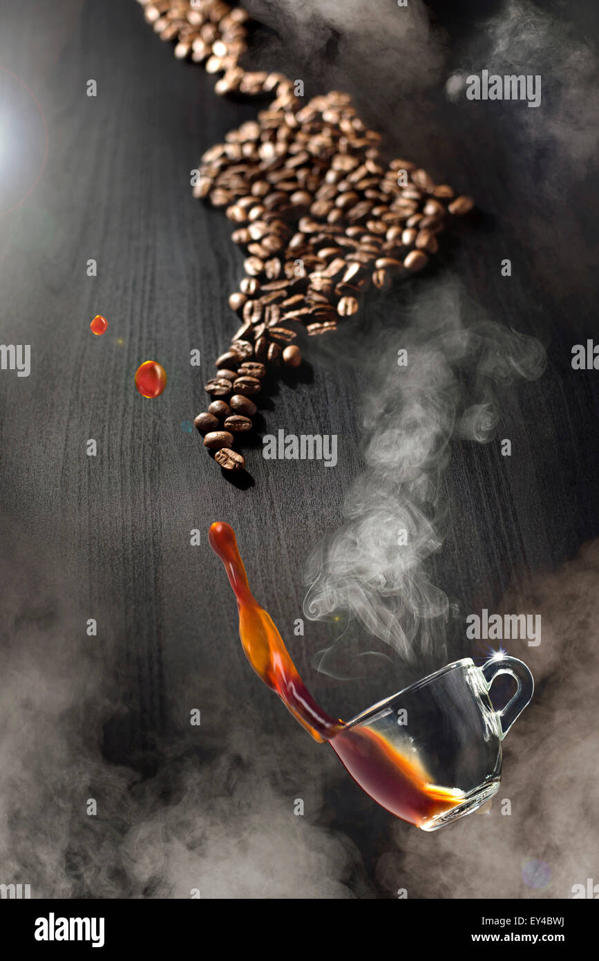 Coffee Cup Floating Through Steam Above Black Table with Coffee Beans Stock Photo