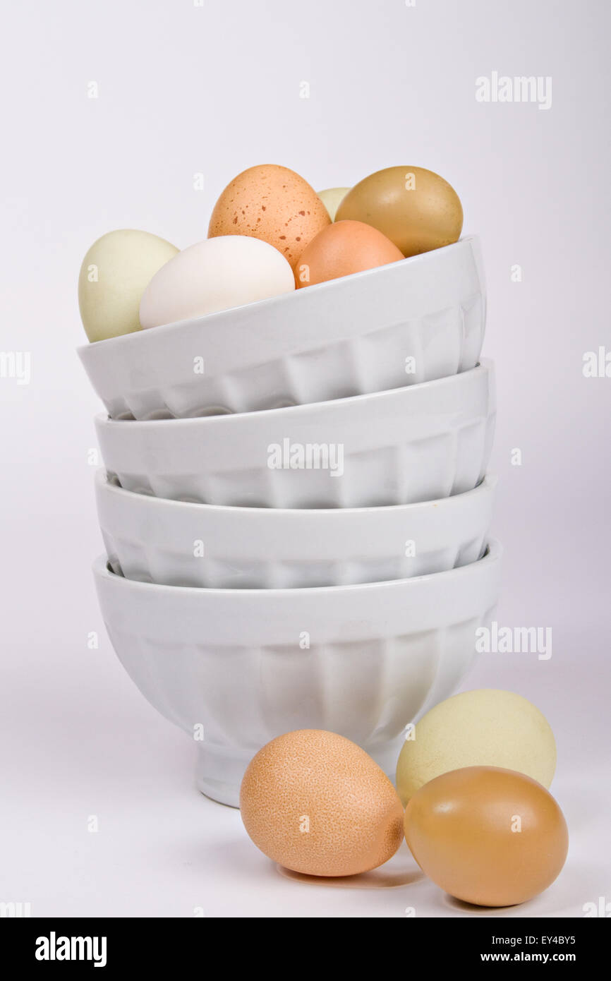 Assortment of Eggs on Top of and Next to a Stack of Bowls Stock Photo