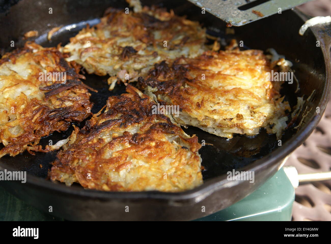 Home made shredded potato hash browns cooking in a cast iron skillet