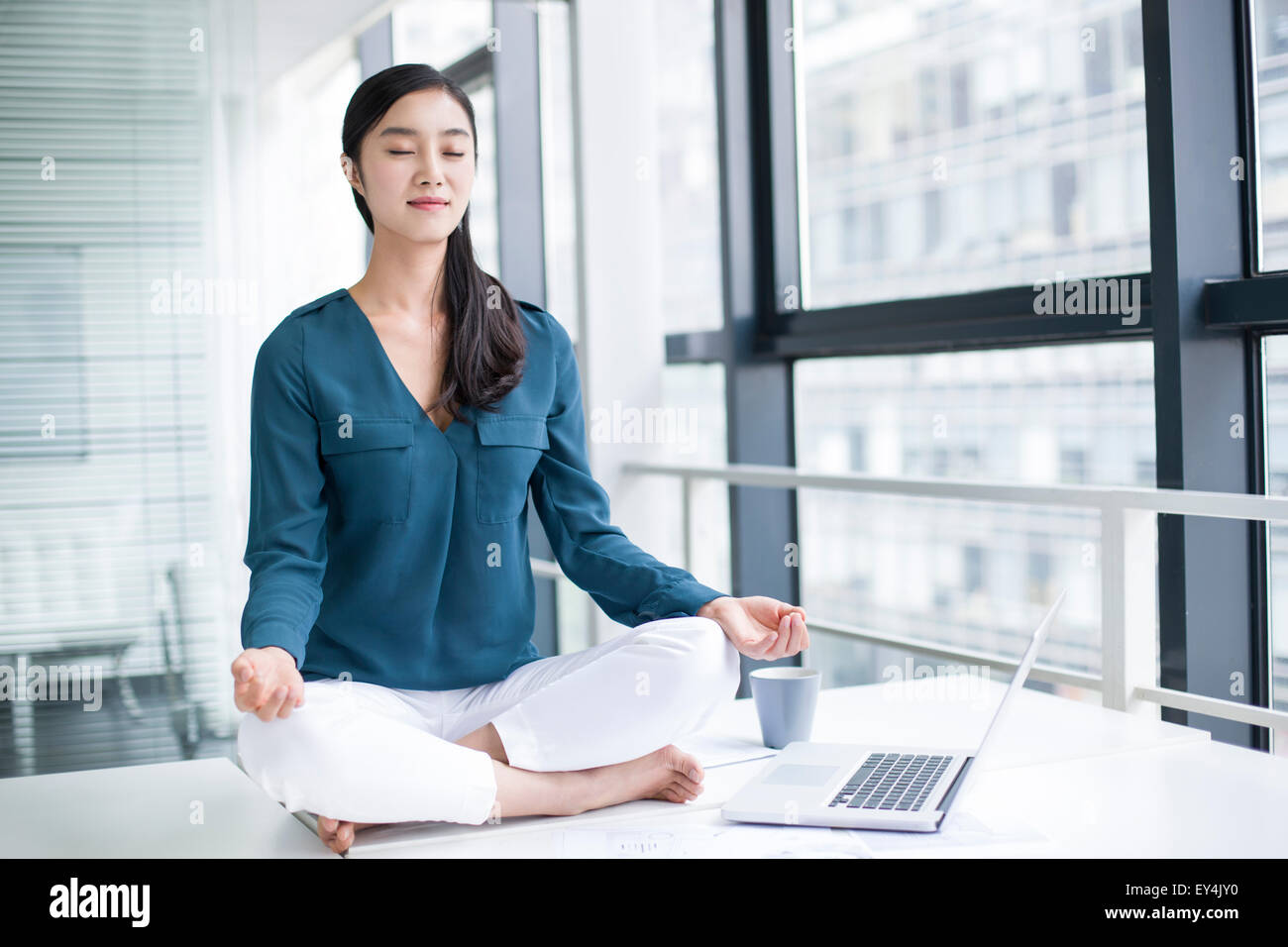 Young businesswoman doing yoga on office desk Stock Photo - Alamy